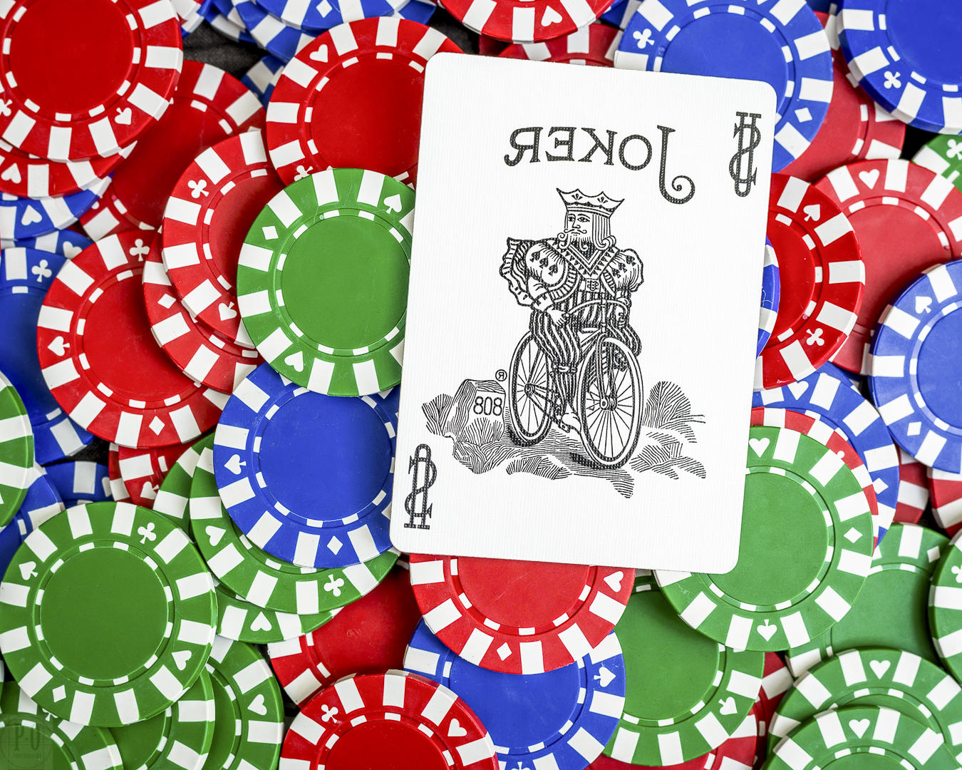 Carte de joker posée sur un tas de jetons de poker rouges, bleus et verts